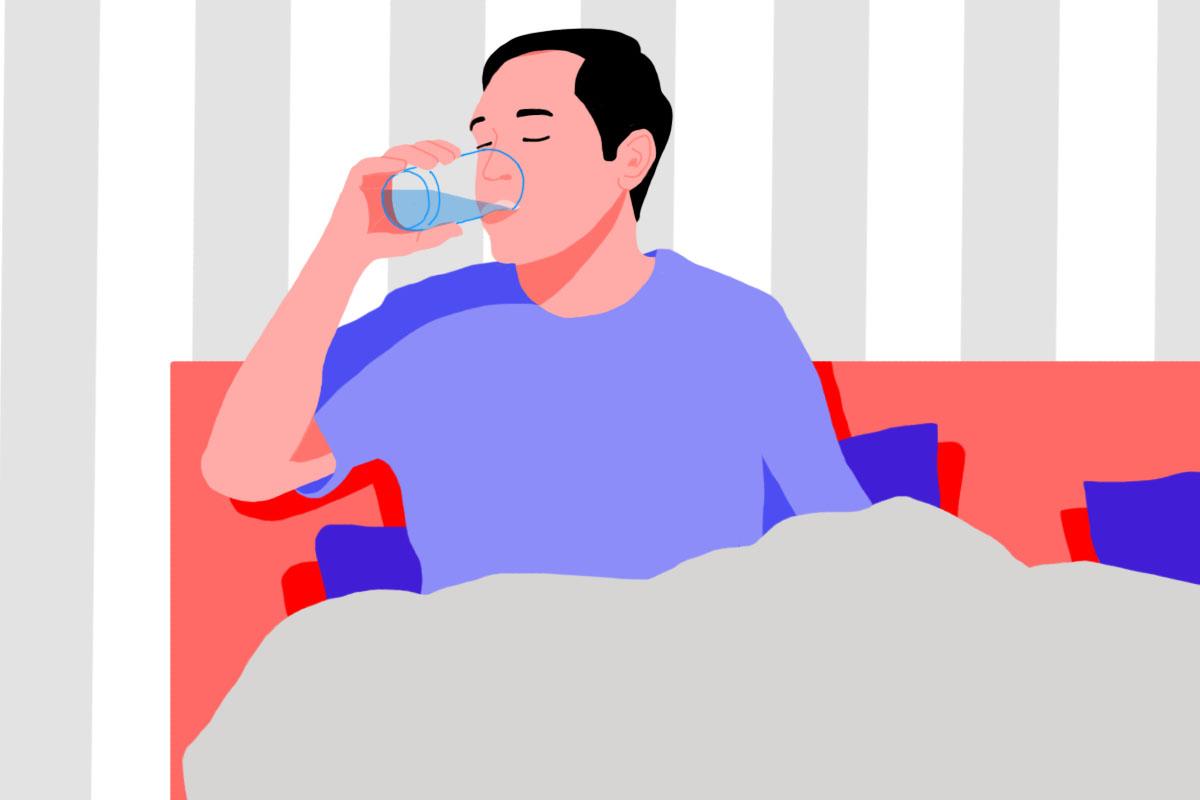 A man sitting on a bed, drinking water before sleep.