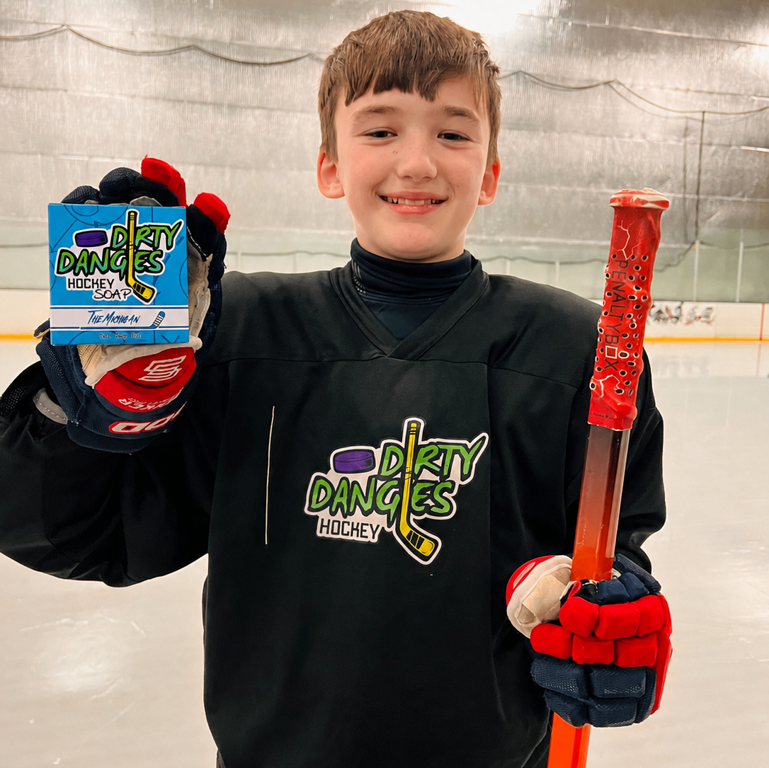 Youth hockey player on the ice holding The Michigan sea salt hockey soap bar and a hockey stick.