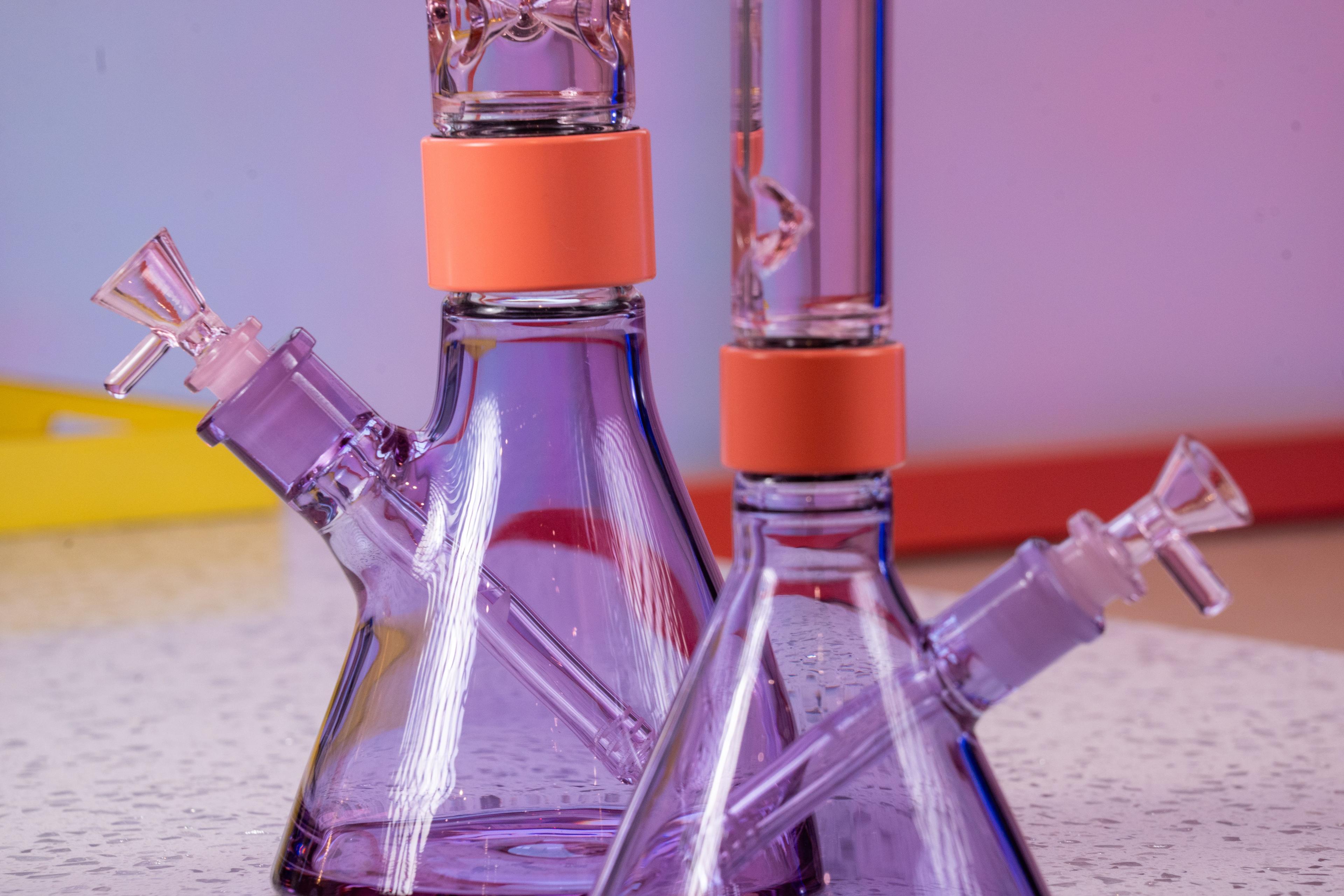 Comparison of two Prism Duo Collection modular bongs in Pink and Purple; standard size on the left and mini beaker on the right. The image highlights the frosted glass-on-glass joints where the 14mm bowl and downstem insert, illustrating the specific areas where resin buildup or hydro-locking typically causes a stuck joint or 'frozen' downstem.