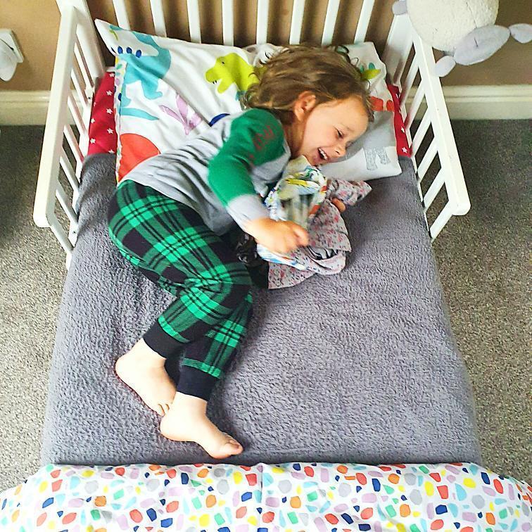 boy wriggling in bed on waterproof bed mat PeapodMat