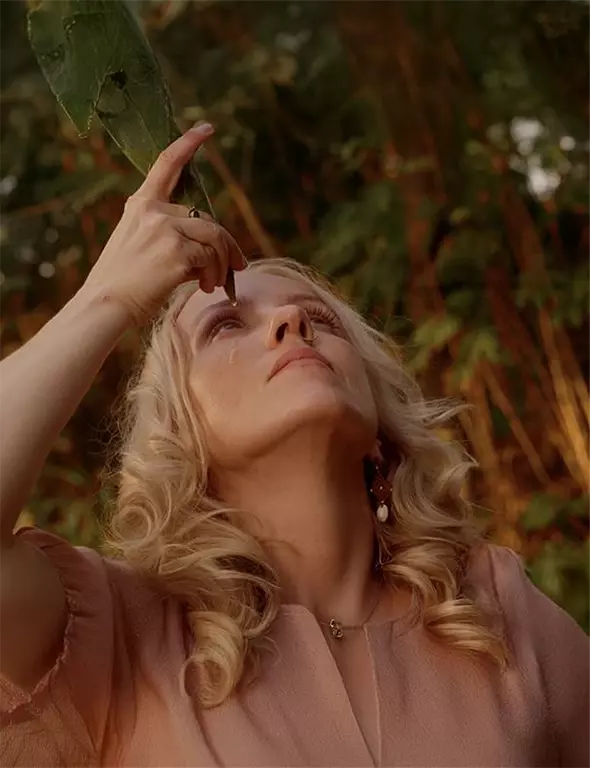 A scene with a woman in the woods applying the product on her face