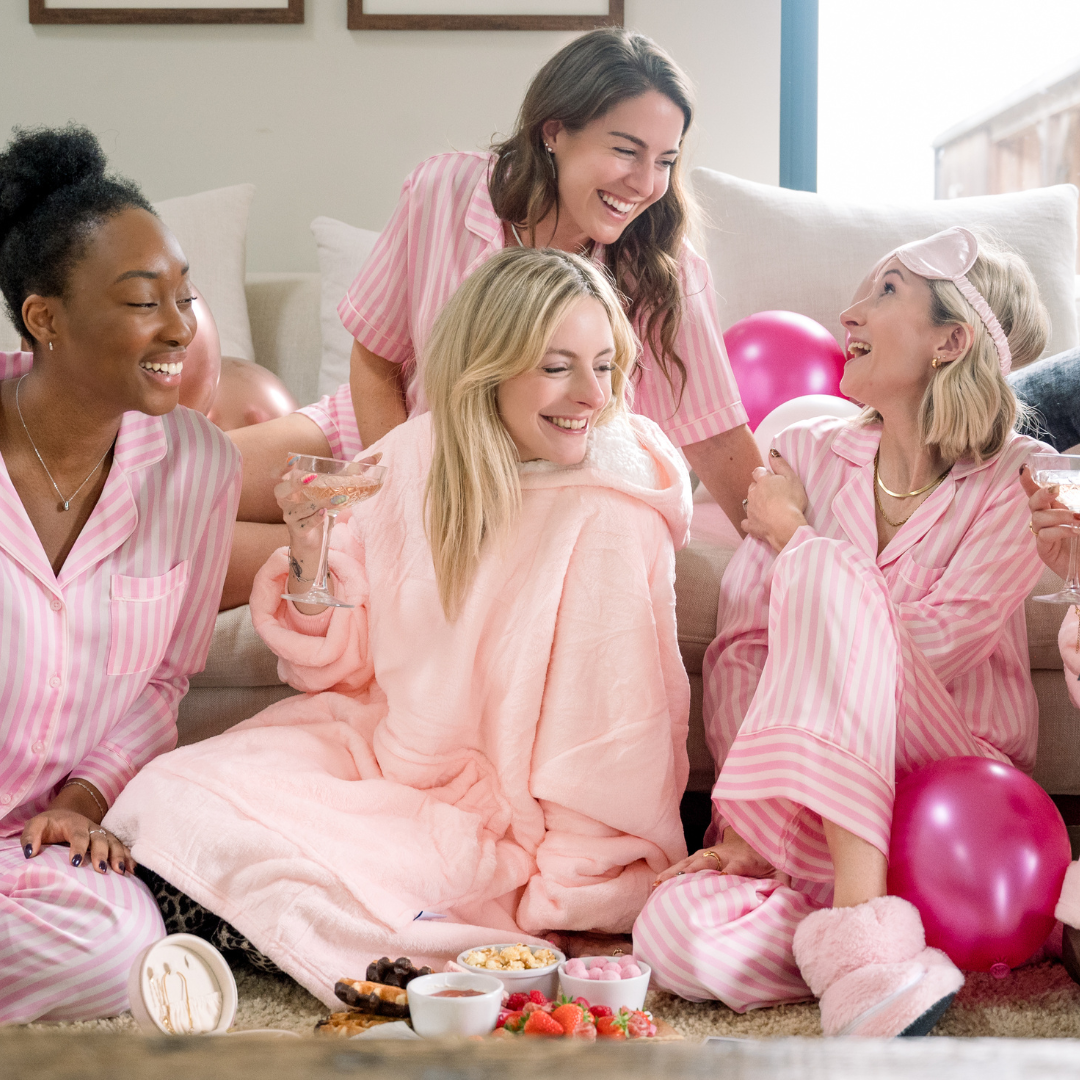 Four women dressed in pink pyjamas enjoying a galentines sleepover