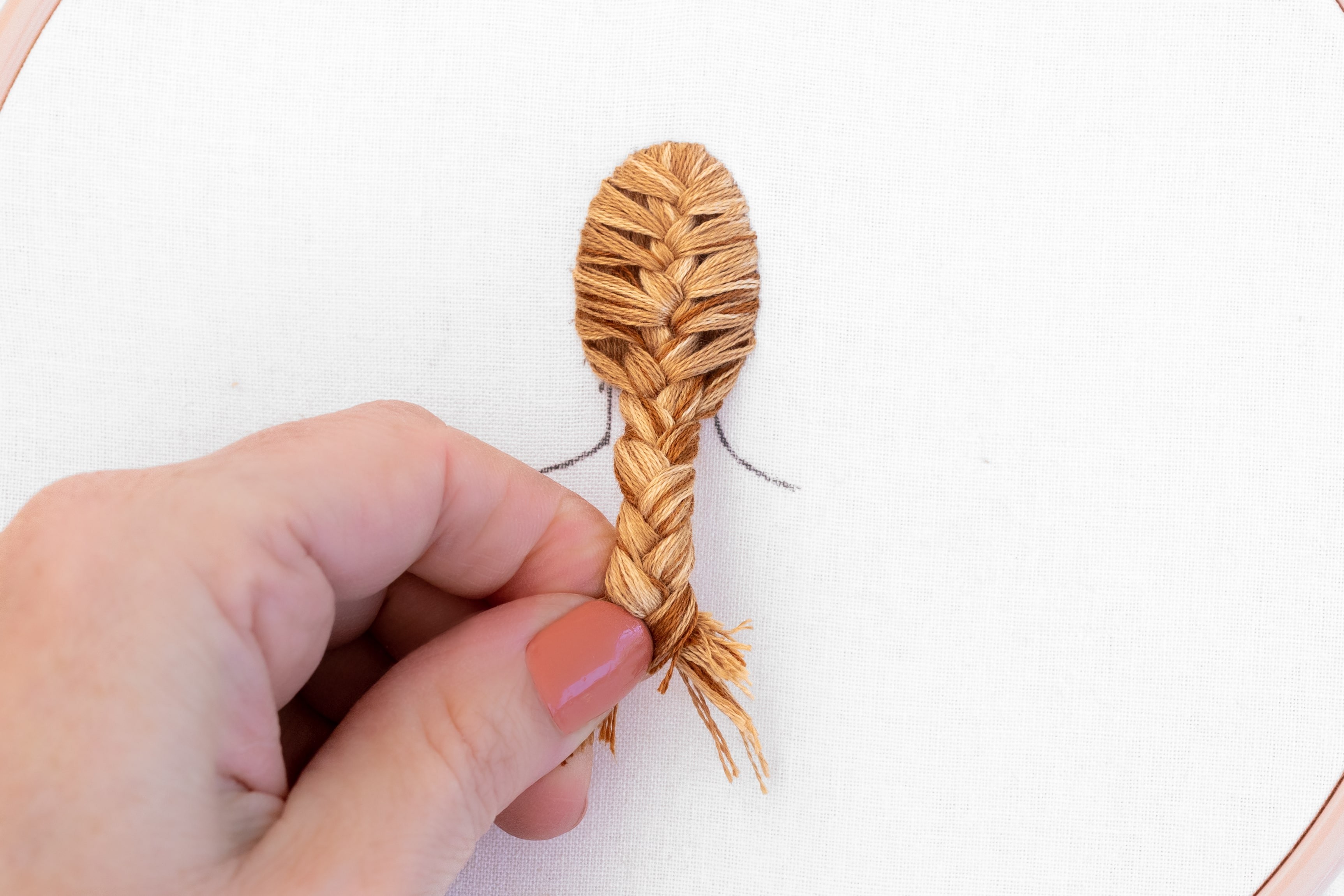 A hand holds a fully plaited fish tail braid.