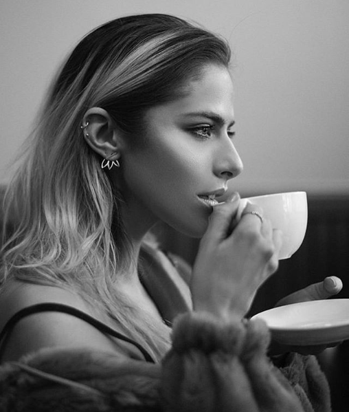 Woman wearing jewelry drinking coffee