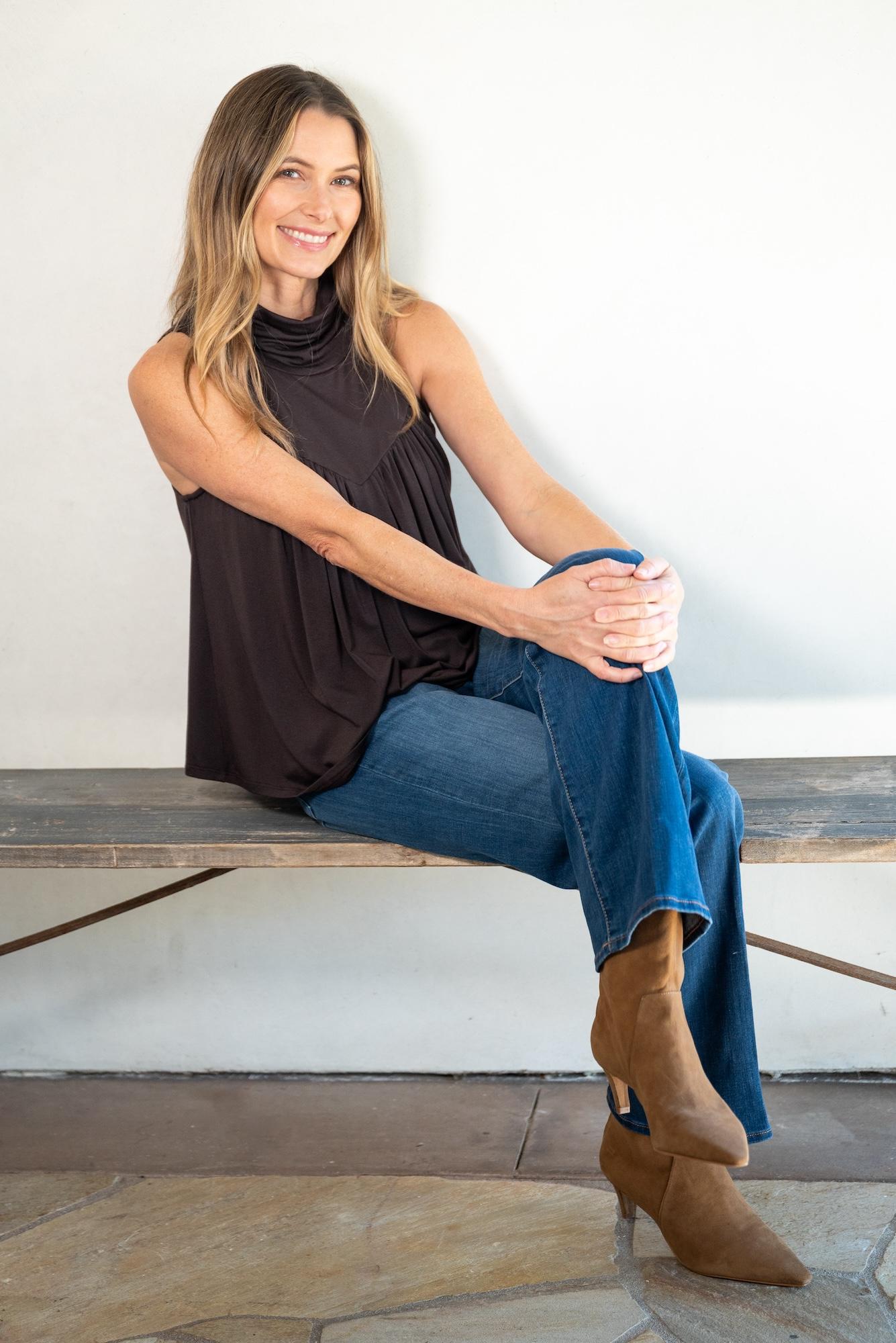 woman wearing the Jjwinks mocktail top sitting on a bench with a fall/autumn vibe outfit