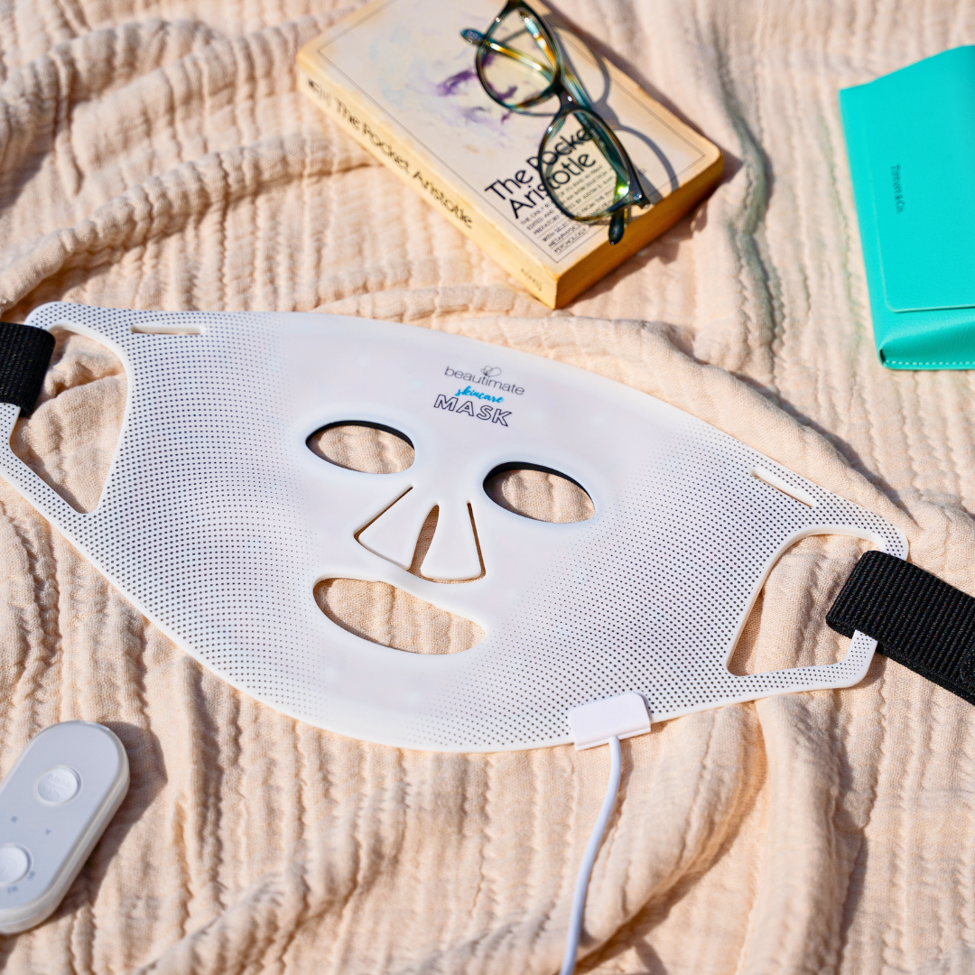 beautimate led mask lifestyle pic, laying on the blanket with a book and glasses