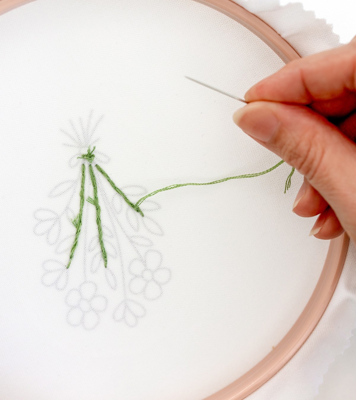 A needle is held away from an embroidered hoop.