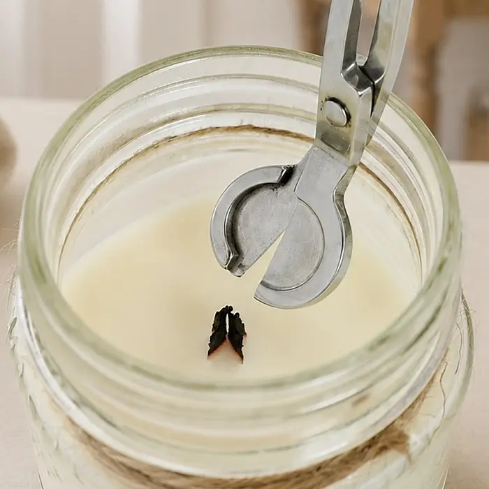 trimming a candle's wooden wick with a wick trimmer