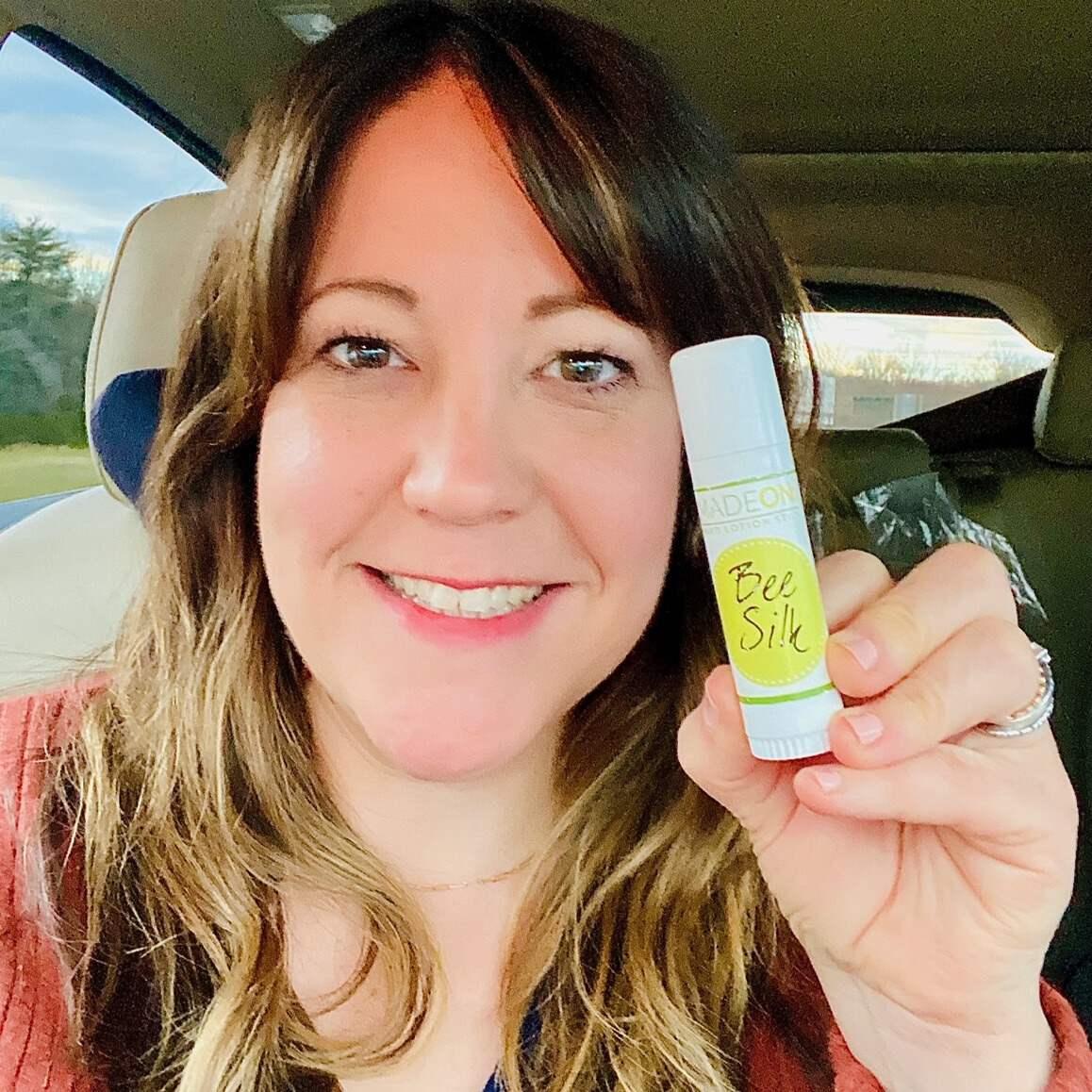 Woman holding up .5 oz Beesilk lotion stick