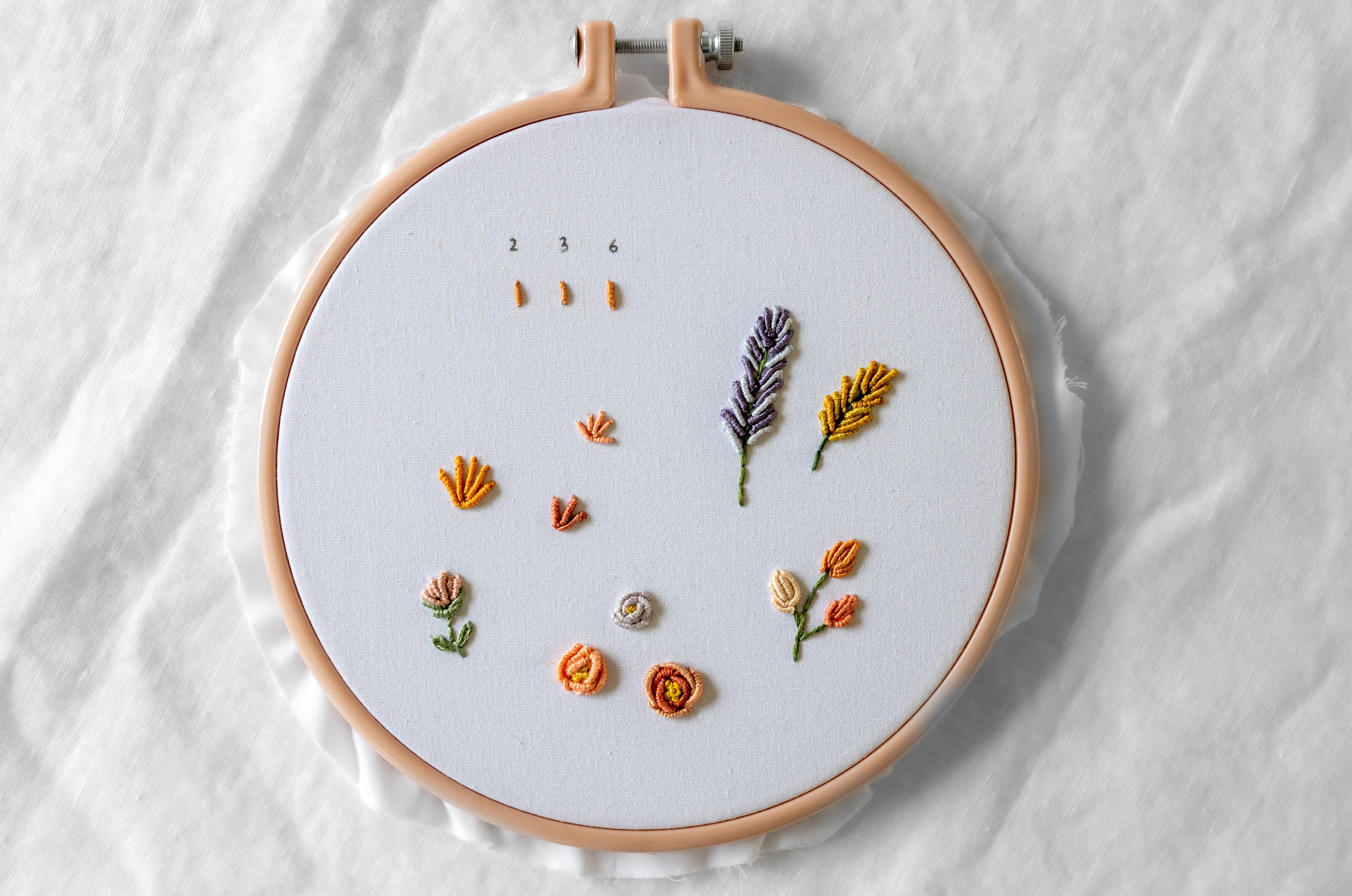 Various flowers made with Bullion Knots are stitched on an embroidery hoop.