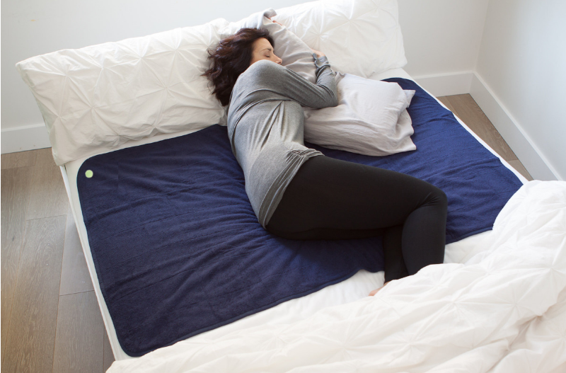 woman laying on large navy PeapodMat in bed with night sweats