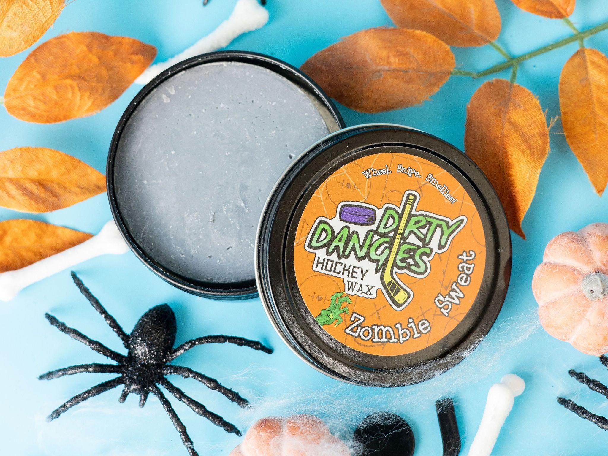 A tin of Halloween dirty dangles hockey zombie sweat pumpkin spice stick wax on a spooky background with spiders and pumpkins