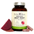 Close up of a bottle of Herbal Roots Organic Beet Root supplement with a few capsules to the front right of the bottle and a small pile of beet root powder with a slice of raw beet root to the left of the bottle