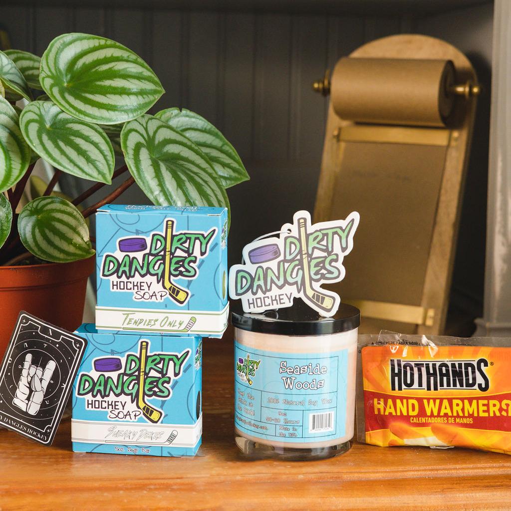 Assorted dirty dangles products on a wood bookshelf with a plant