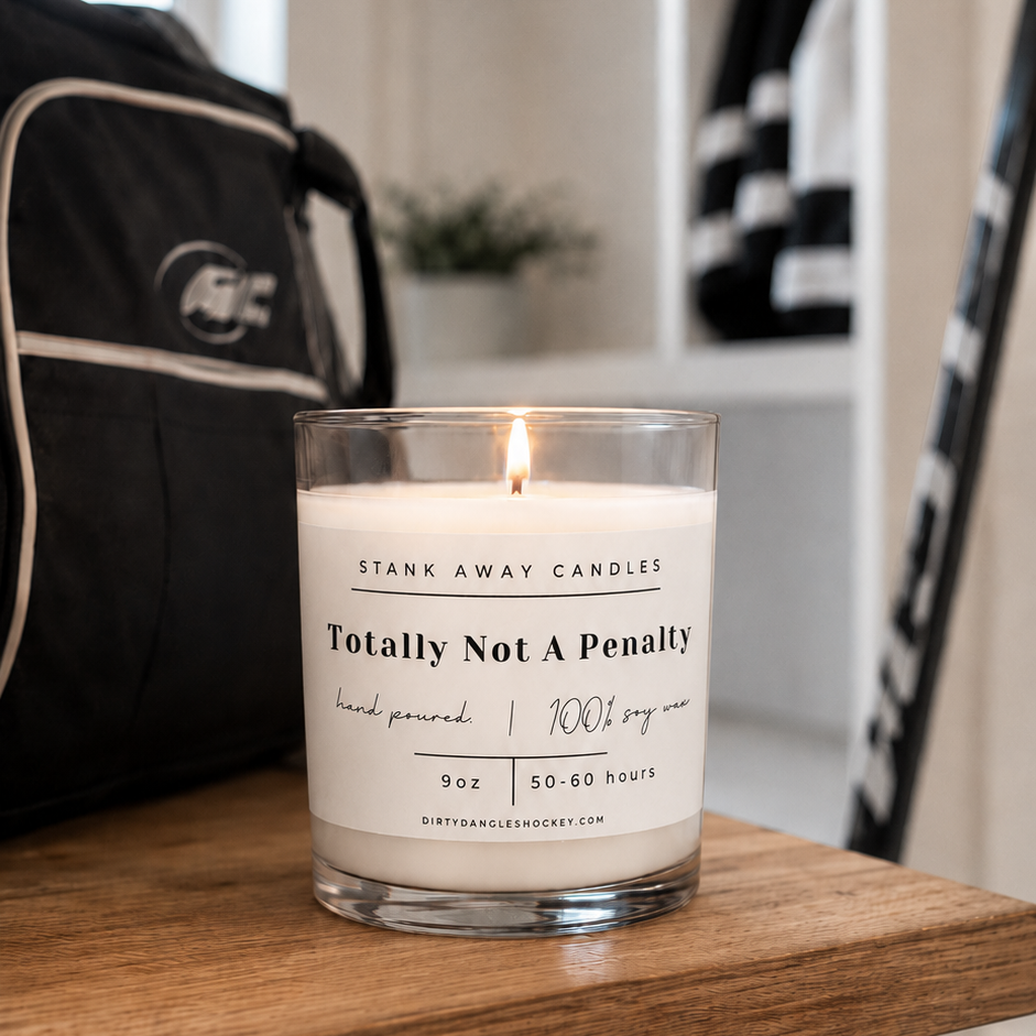 A white scented hockey candle on a wooden bench with hockey gear. Totally not a penalty