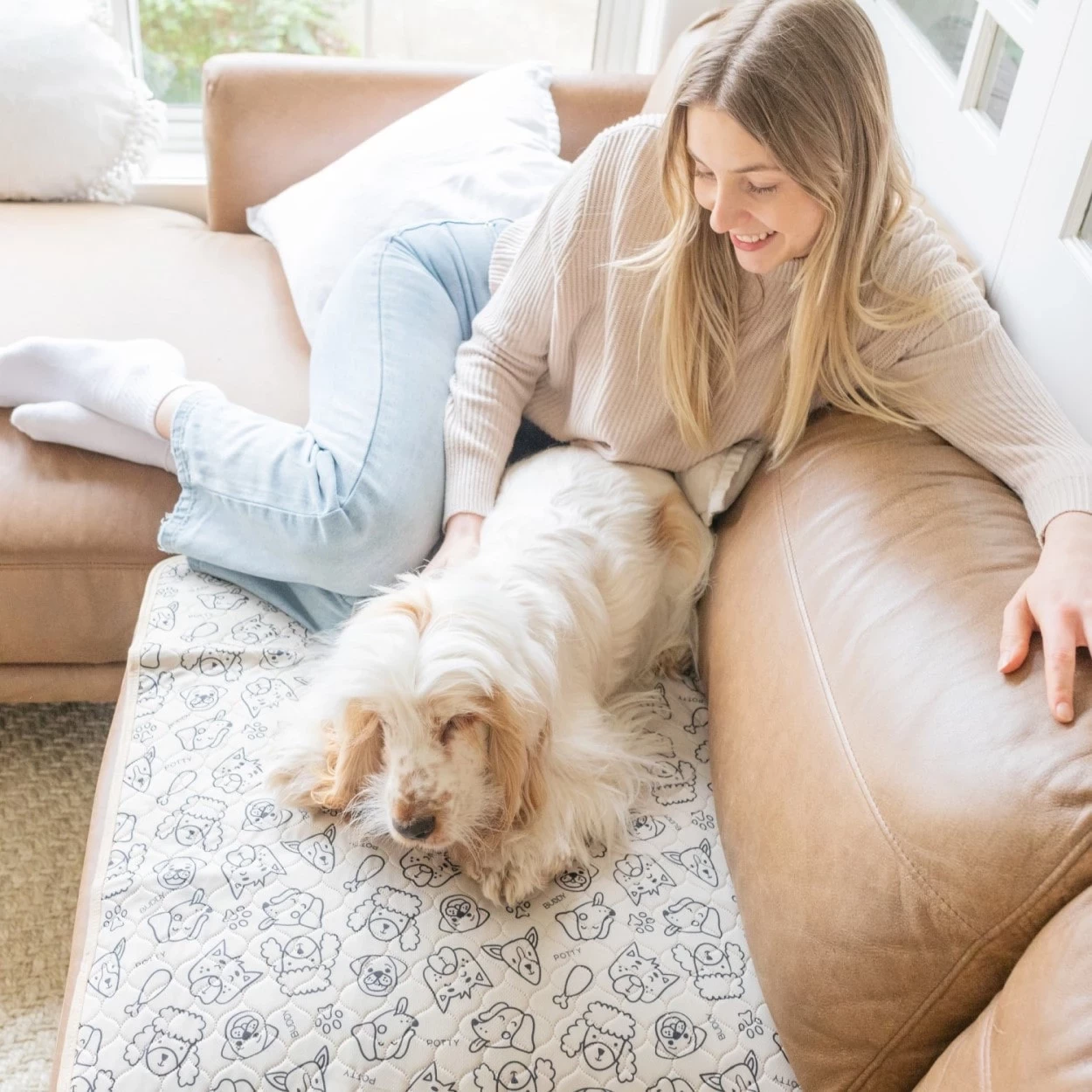 A girl and her old dog relaxing on the couch, with the dog on a reusable potty pad
