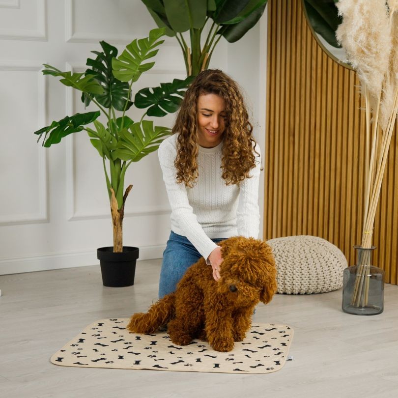 Woman petting dog who is sitting on a reusable dog potty pad