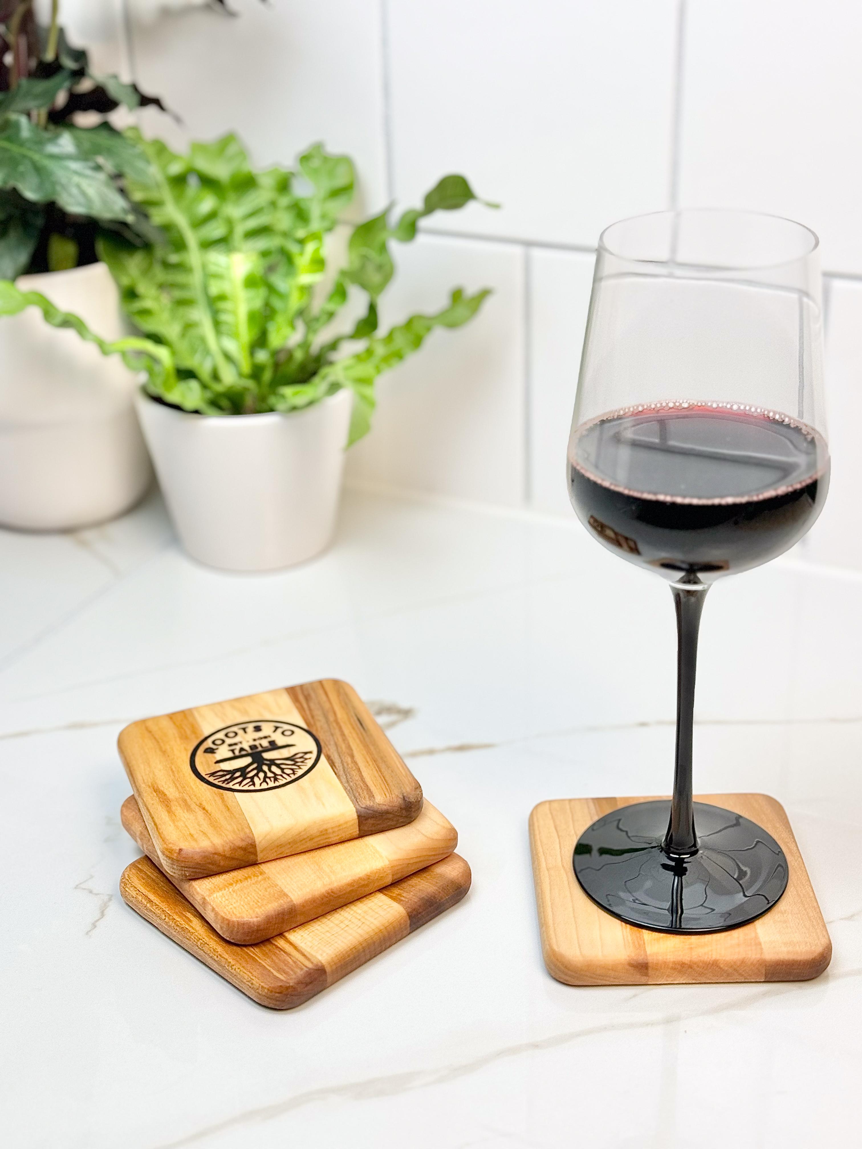 A set of 4 square maple wood drink coasters, showcasing a glass of wine setting atop one coaster