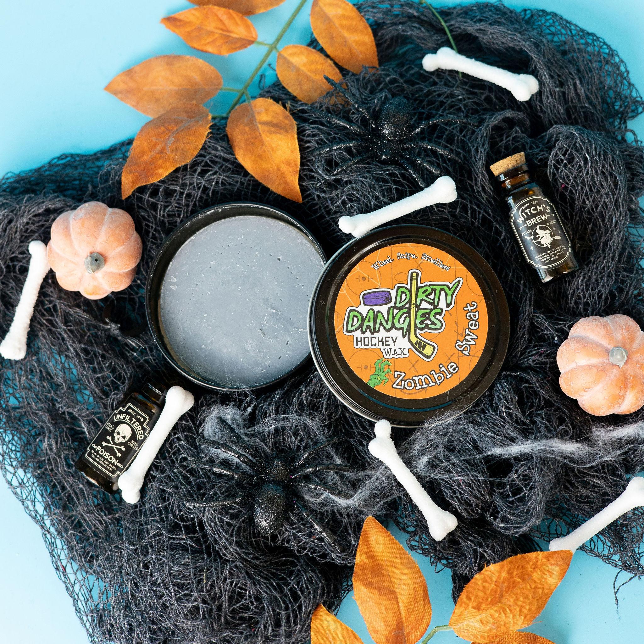 A tin of Halloween dirty dangles hockey zombie sweat pumpkin spice stick wax on a spooky background with spiders, bones and pumpkins