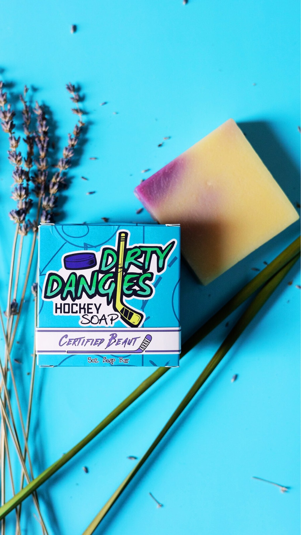 A purple and yellow bar of dirty dangles hockey soap on a lemongrass.