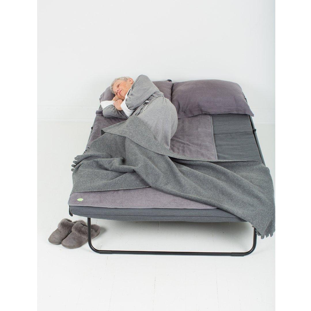 Elderly woman sleeping on large grey PeapodMat - washable and 100% leakproof bed mat.