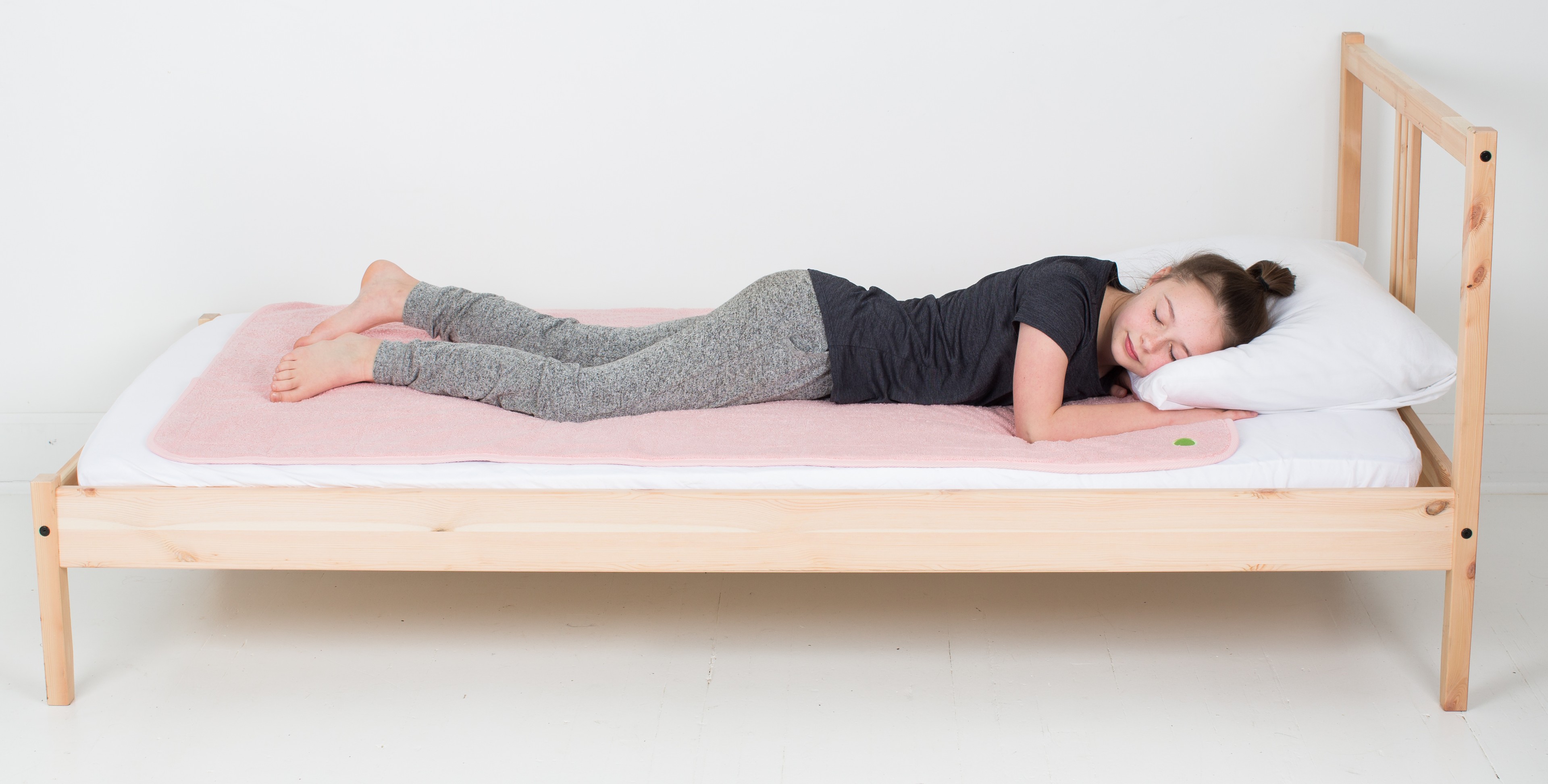 teenage girl sleeping on pink PeapodMat washable bed pad