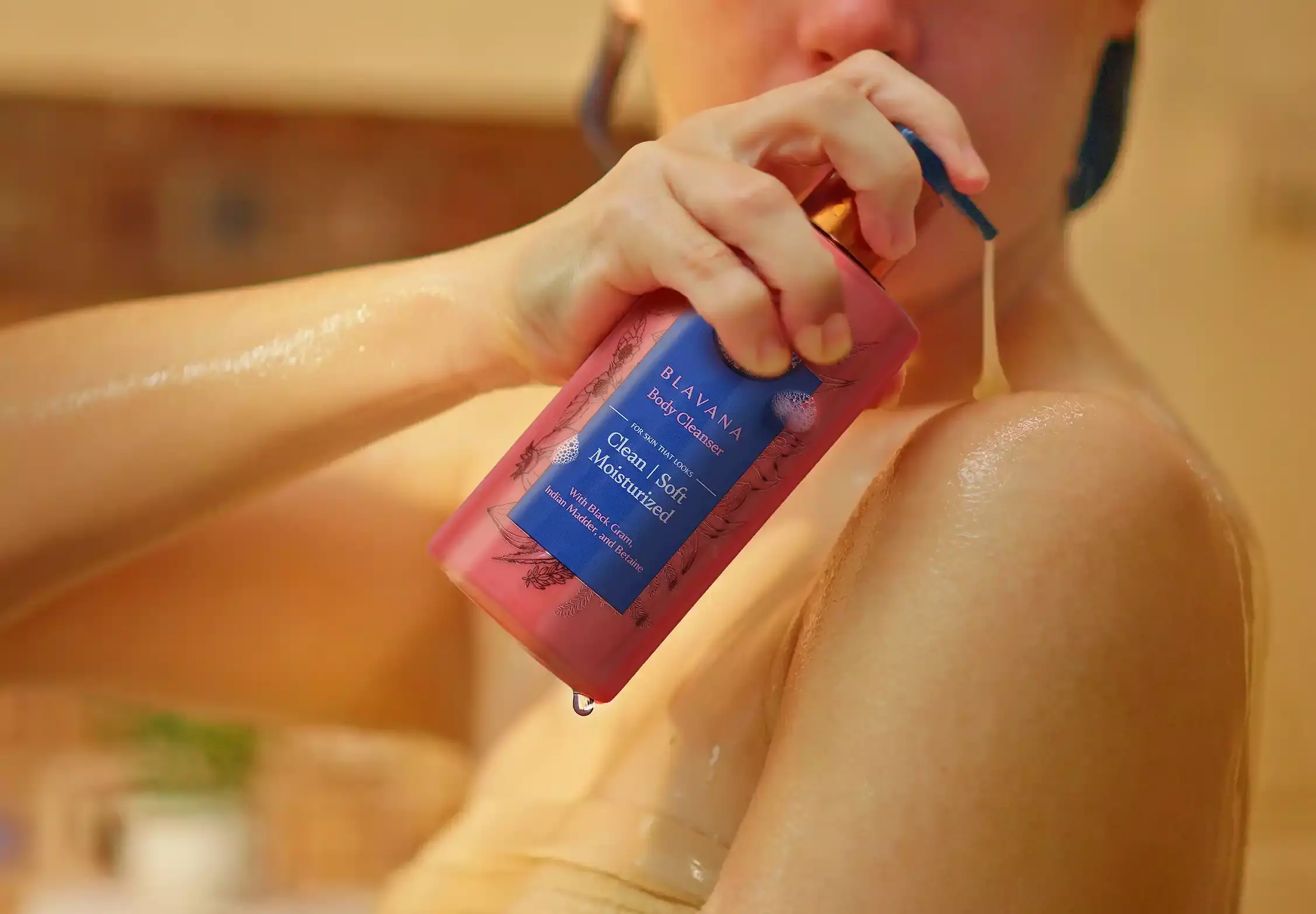 2. The image shows a woman hand holding a Blavana cleanser bottle. She is gently squeezing the bottle, causing a clear liquid to come out of the bottle.