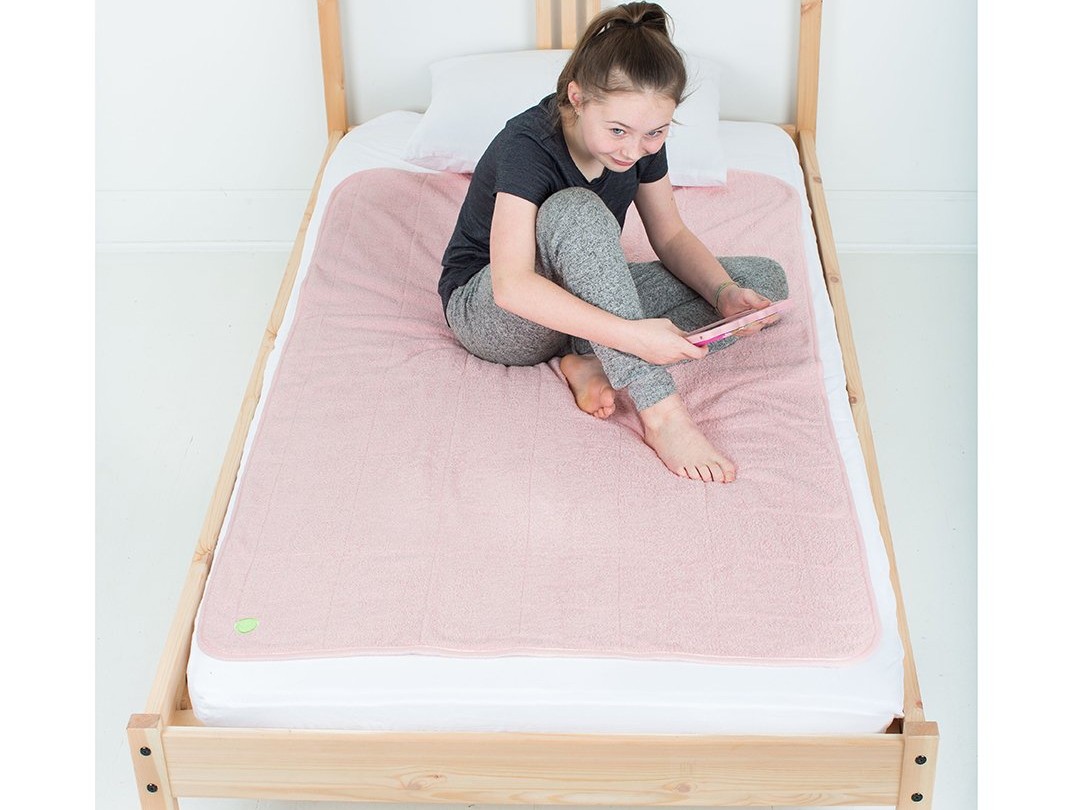 girl sitting on the bed with large pink PeapodMat