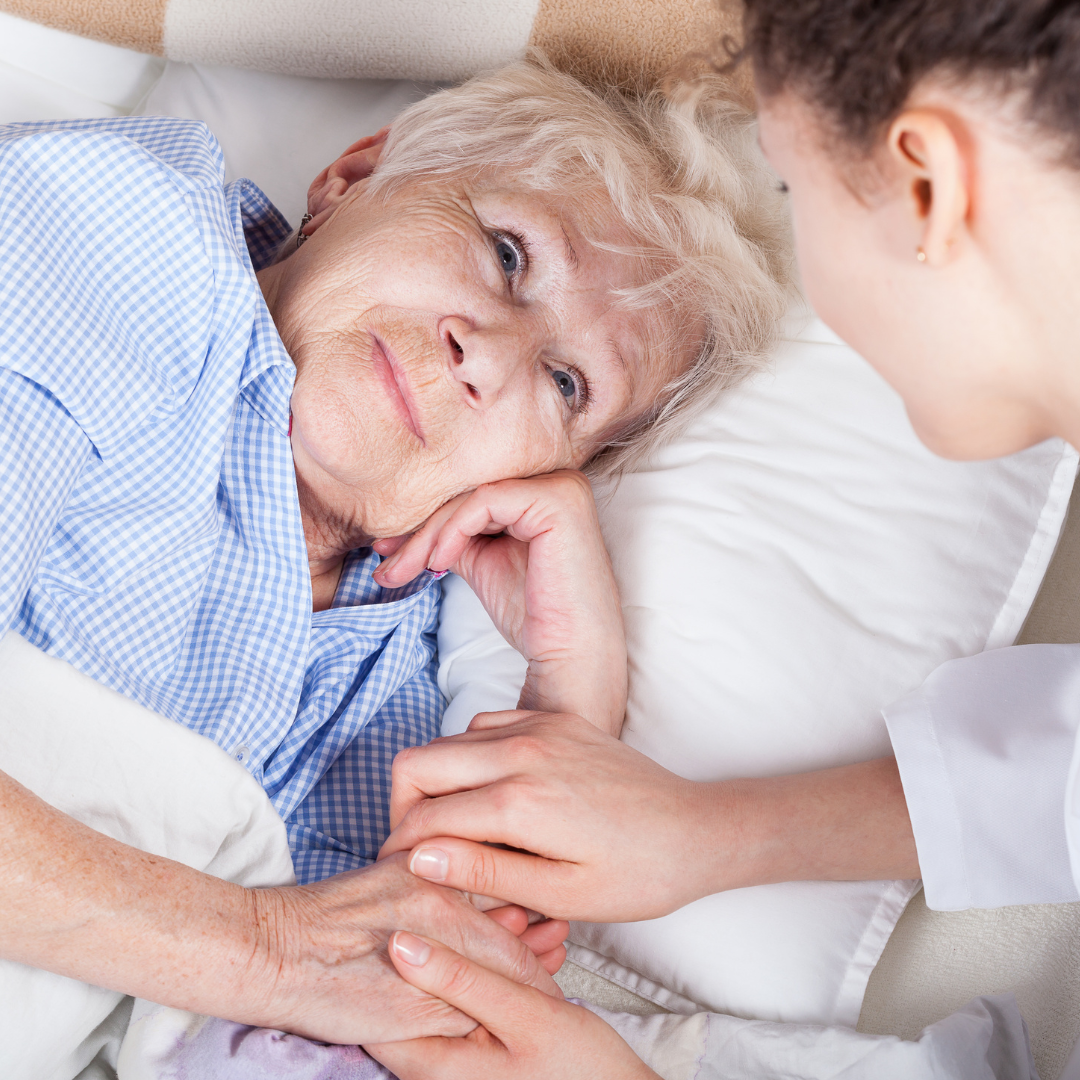 Young woman looking after an elderly lady in bed