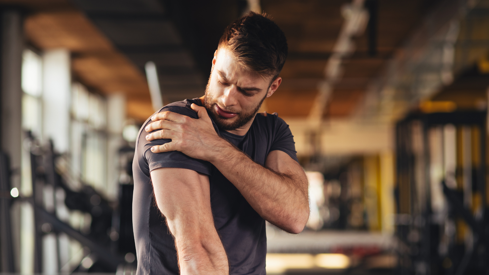 Man in gym clutching shoulder in pain