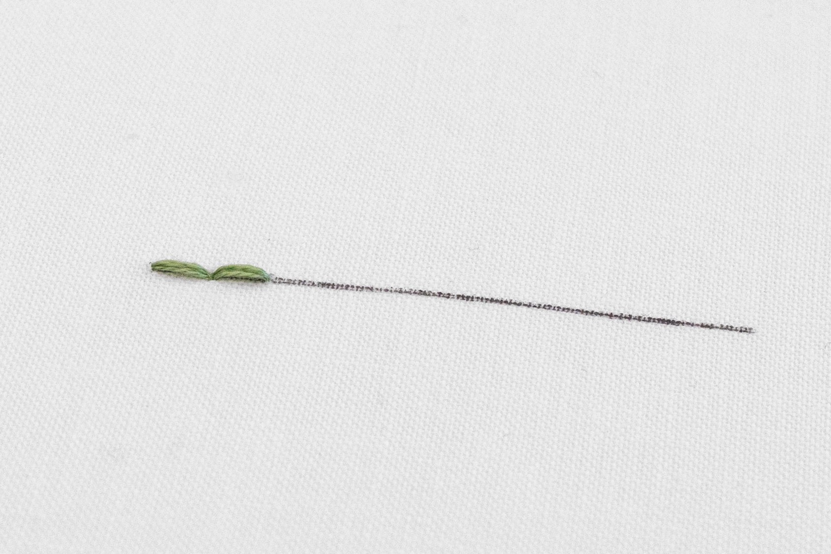 A second stitch has been created on a piece of embroidery fabric.