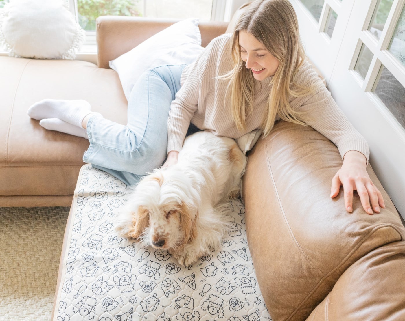 A girl and her old dog relaxing on the couch, with the dog on a reusable potty pad