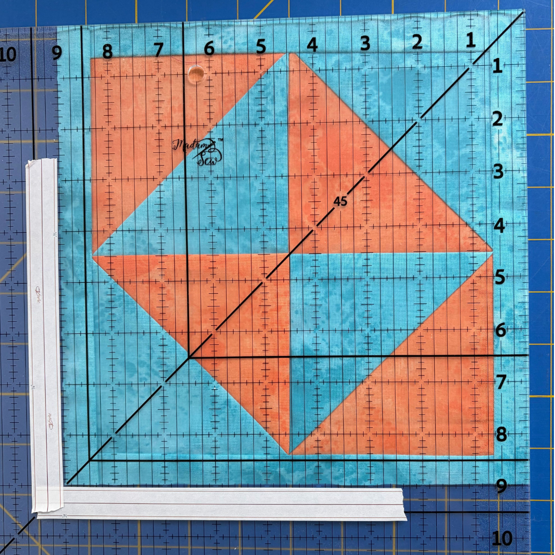 A perfectly squared 9” block with the 12.5” Square Up ruler sitting on top of it and Washi Tape showing the 9” lines.