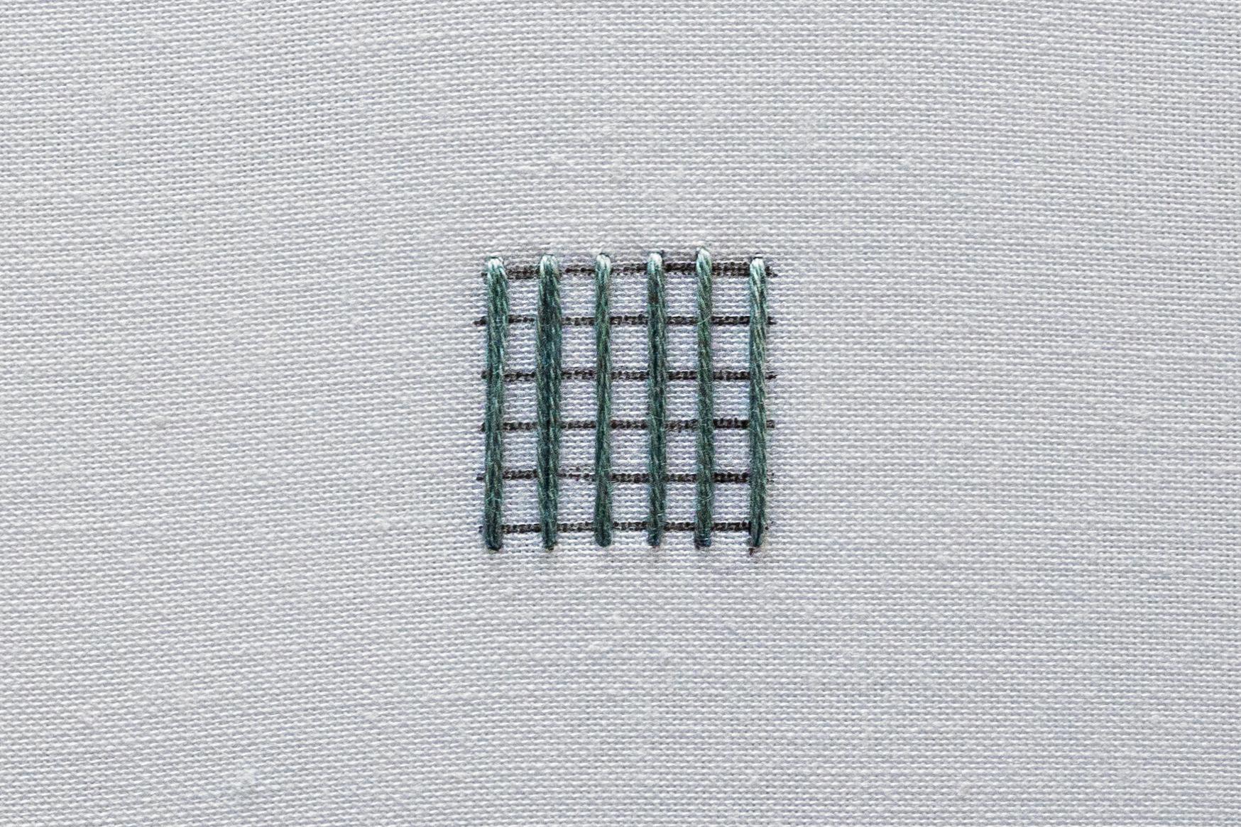 Evenly spaced vertical stitches laid across a shape, forming the warp.