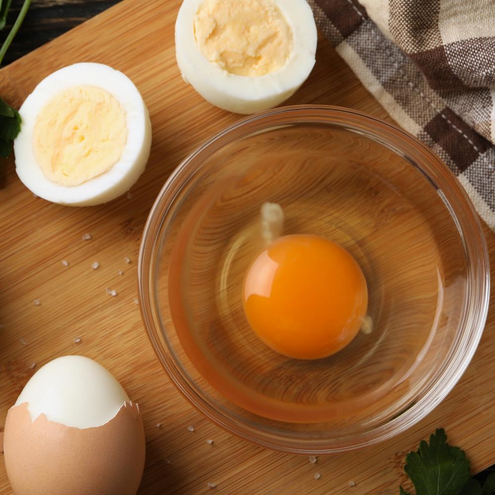 Board with boiled eggs, napkin and parsley on wooden background