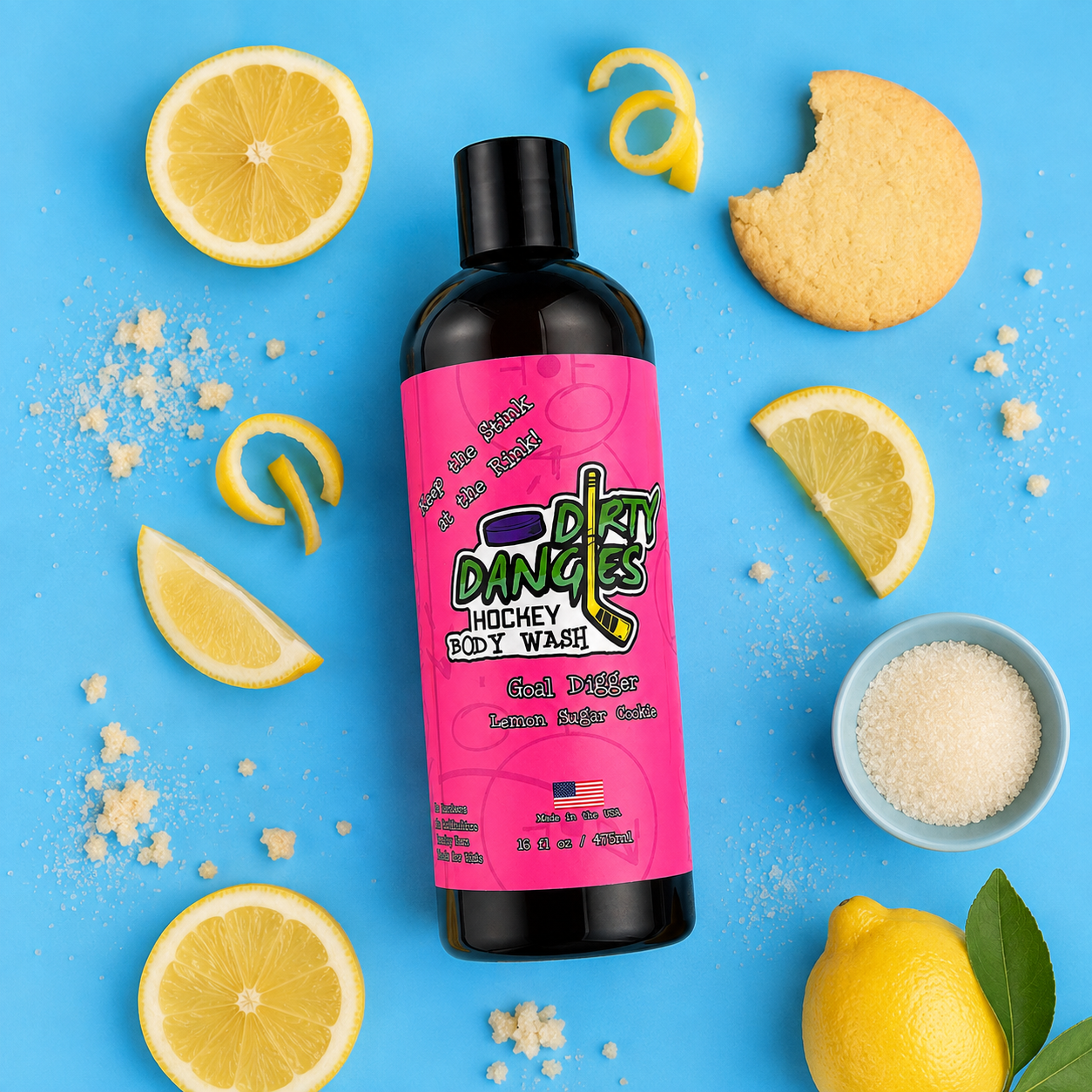 a bottle of goal digger girls lemon sugar cookie scented hockey body wash with a pink label on a blue background with lemons, sugar and cookies.