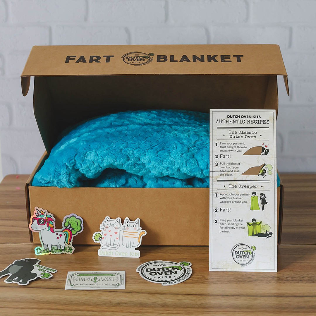 A blue dutch oven kit sits on a wood background with a recipe card and stickers. Fart Blanket