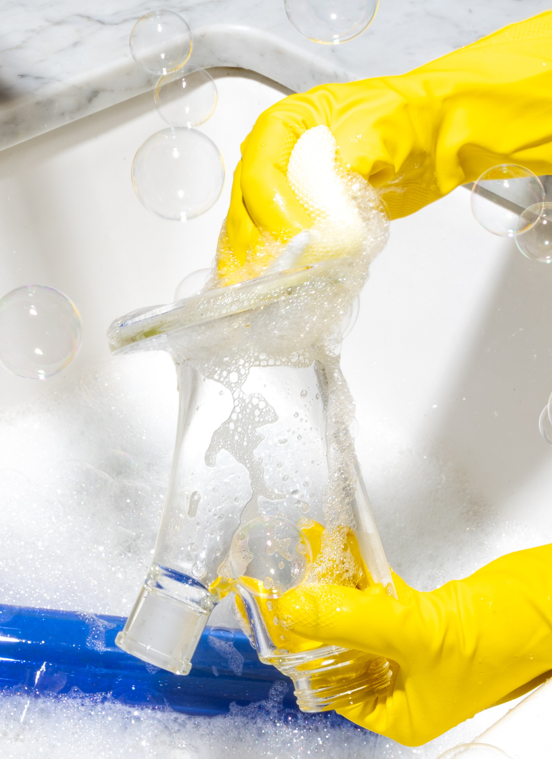 A gloved worker thoroughly cleaning a modular glass bong base to prepare the surface for decal application, ensuring a flawless kiln-fired finish.