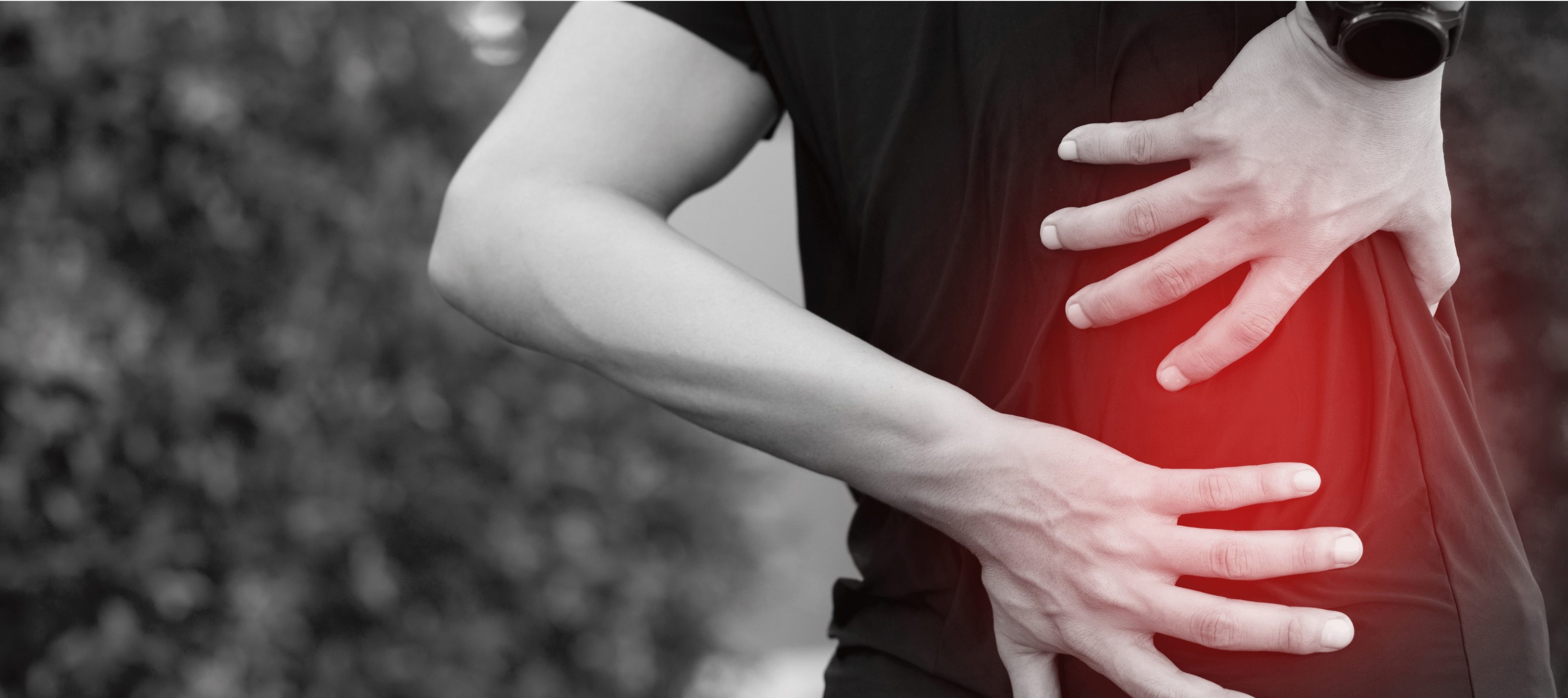 Person clutching their lower back where a glowing red indicates pain