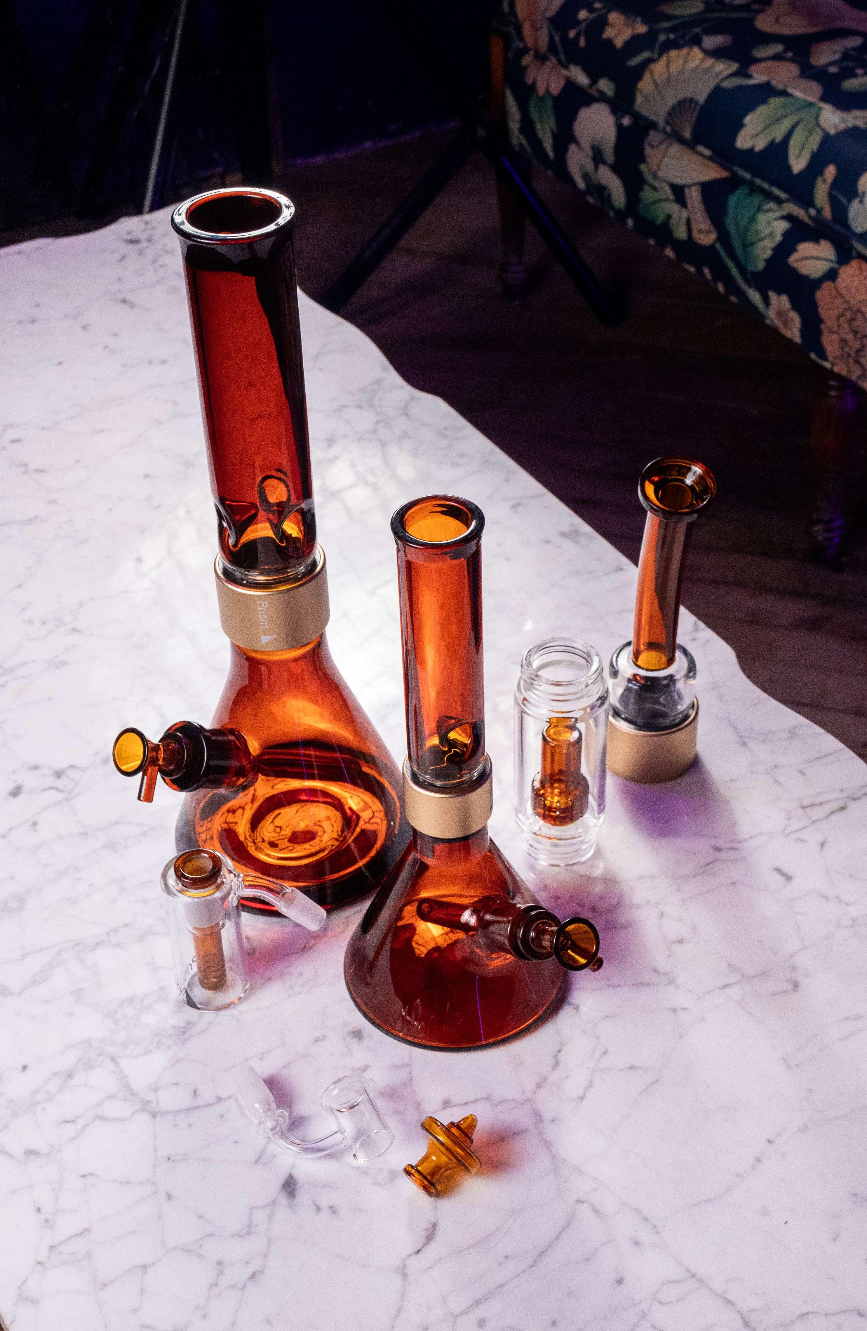 A collection of Prism Amber glass accessories and modular parts, featuring amber ash catchers, showerhead percolators, bent mouthpieces, 14mm bowls, and angular carb caps for the modular halo system.