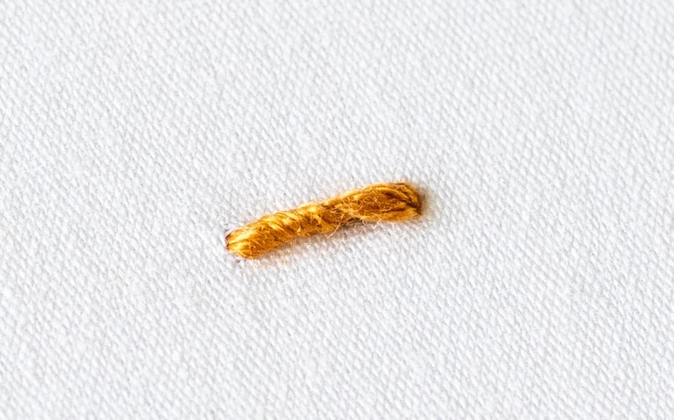 A bullion knot has been created with gold thread.