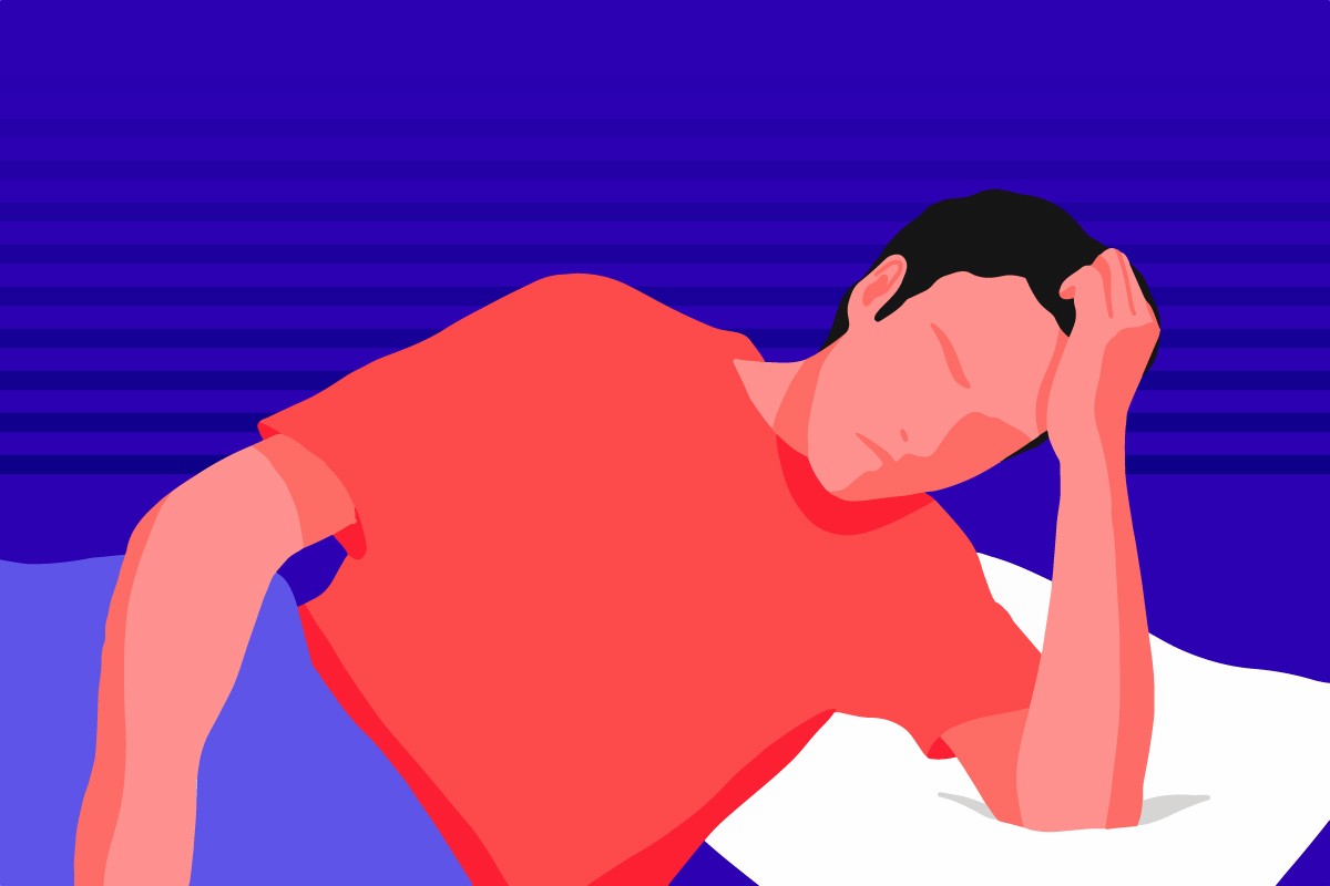 A man lying down in bed suffering from a migraine.