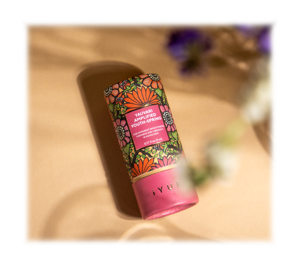 Youth Spring Bottle lying on a soft cloth with herbs and spices around it
