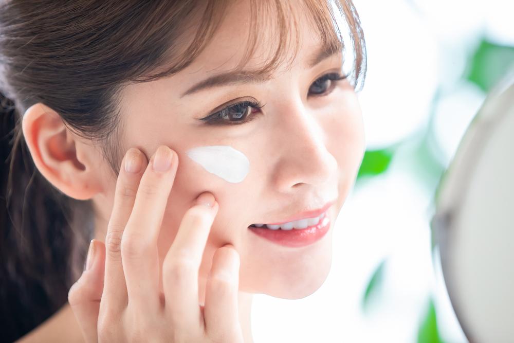 Woman applying sunscreen as the last step in her skincare routine.
