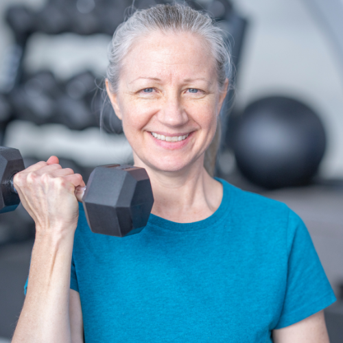 senior woman smiling as she lifts up a dumbbell.