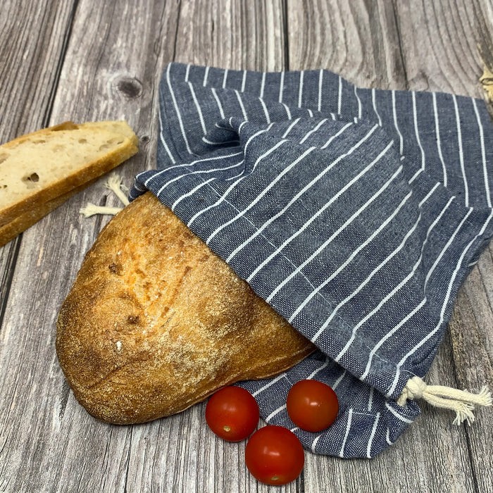 blue organic cotton bread bag with loaf of bread sticking out of it.