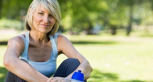 Blonde Woman in Blue Shirt Sitting Outside in Park with Water Bottle