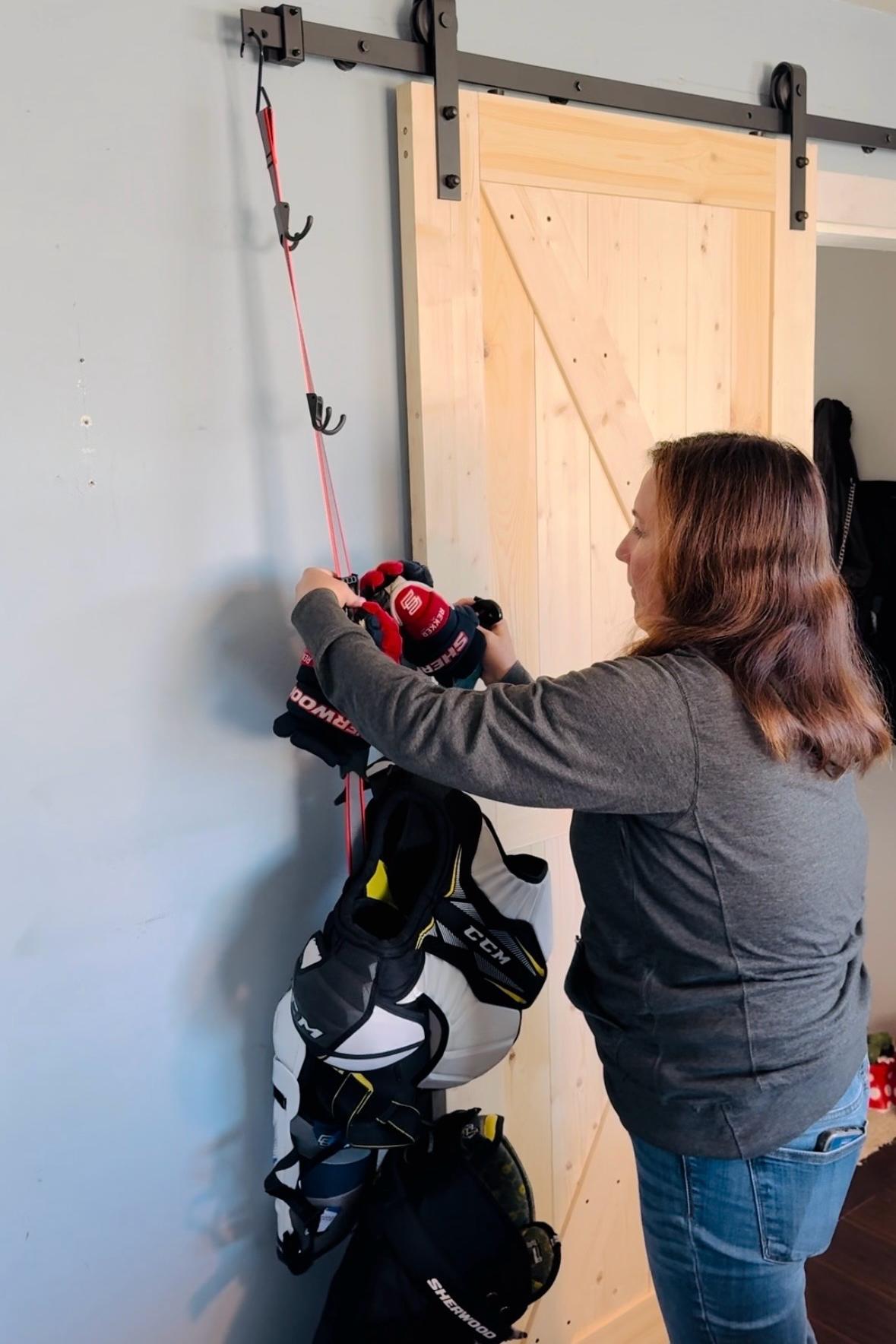 A hockey mom hanging hockey gear on an UTTy portable gear hanger