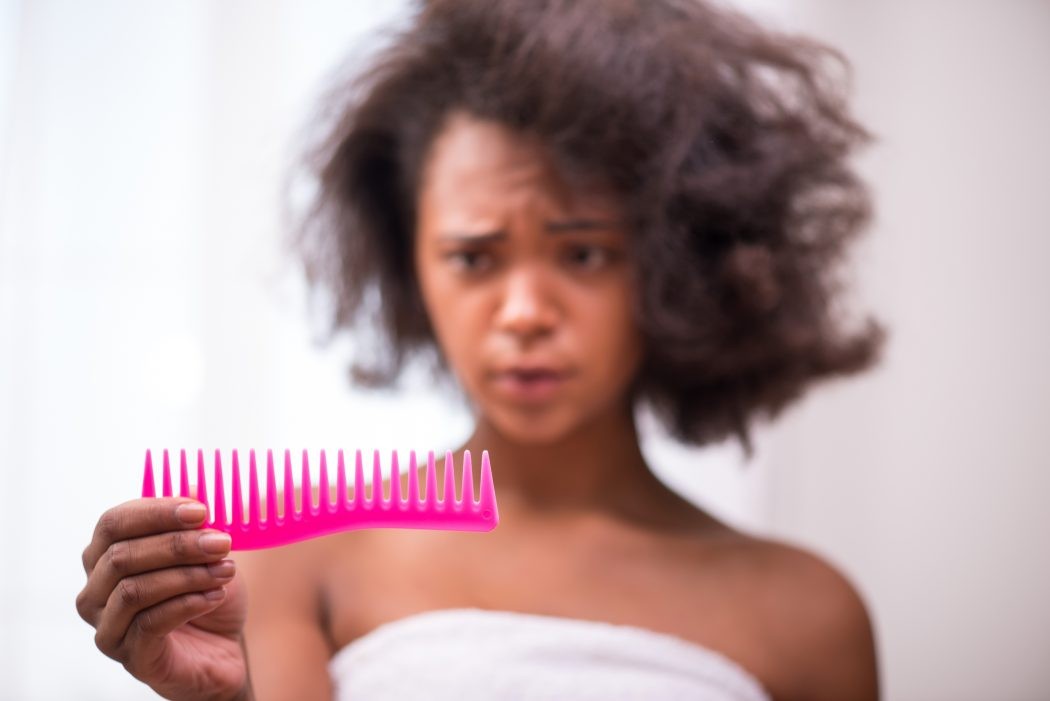 woman stressed out about hair loss in her comb