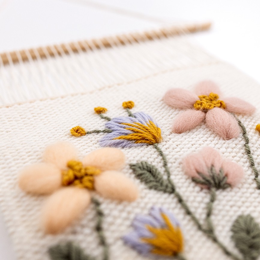 This is a close up image of the weaving pattern 'Woven Meadow' that uses embroidered details with wool.